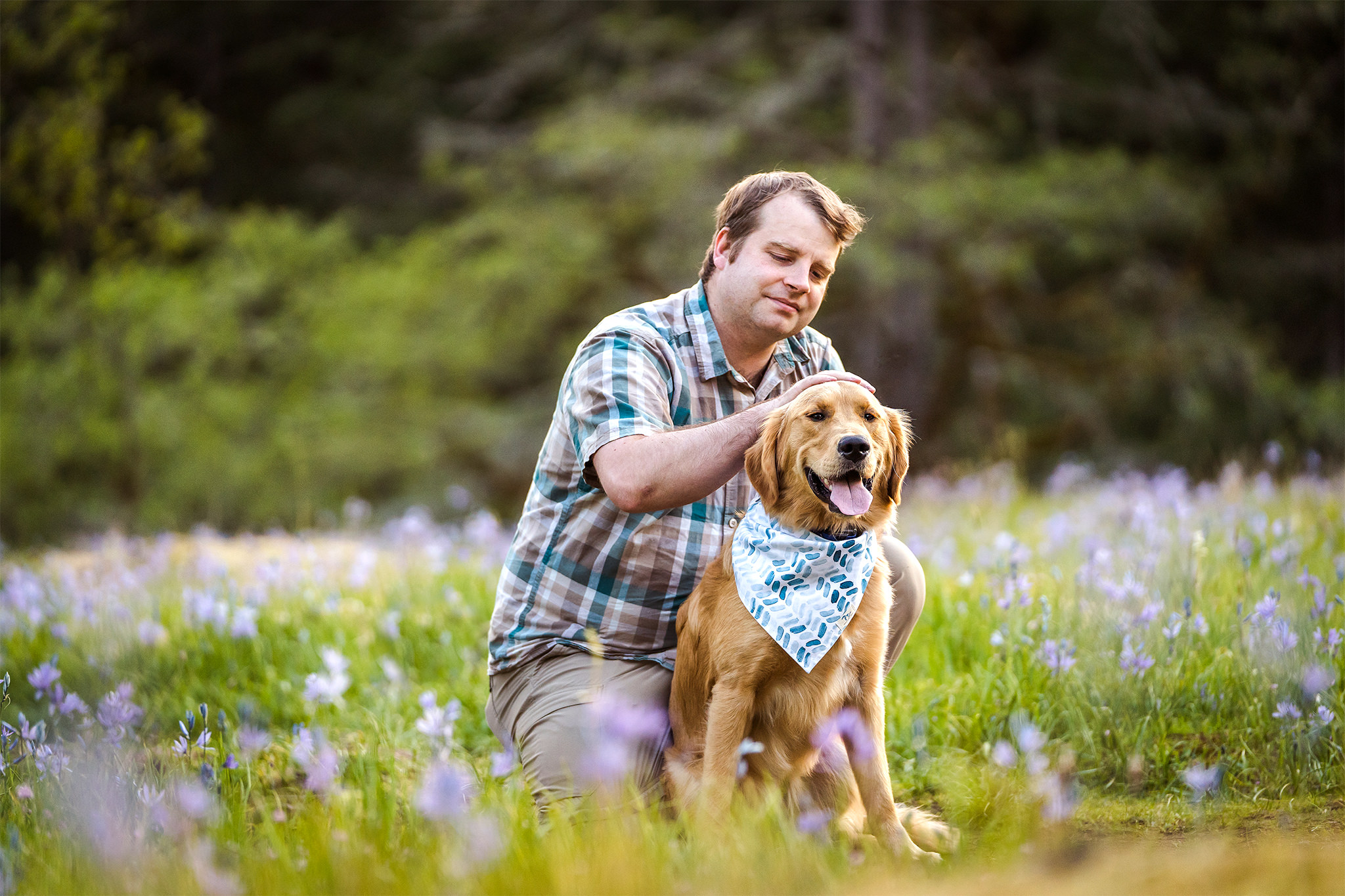 man pets his dog in a field of purple flowers