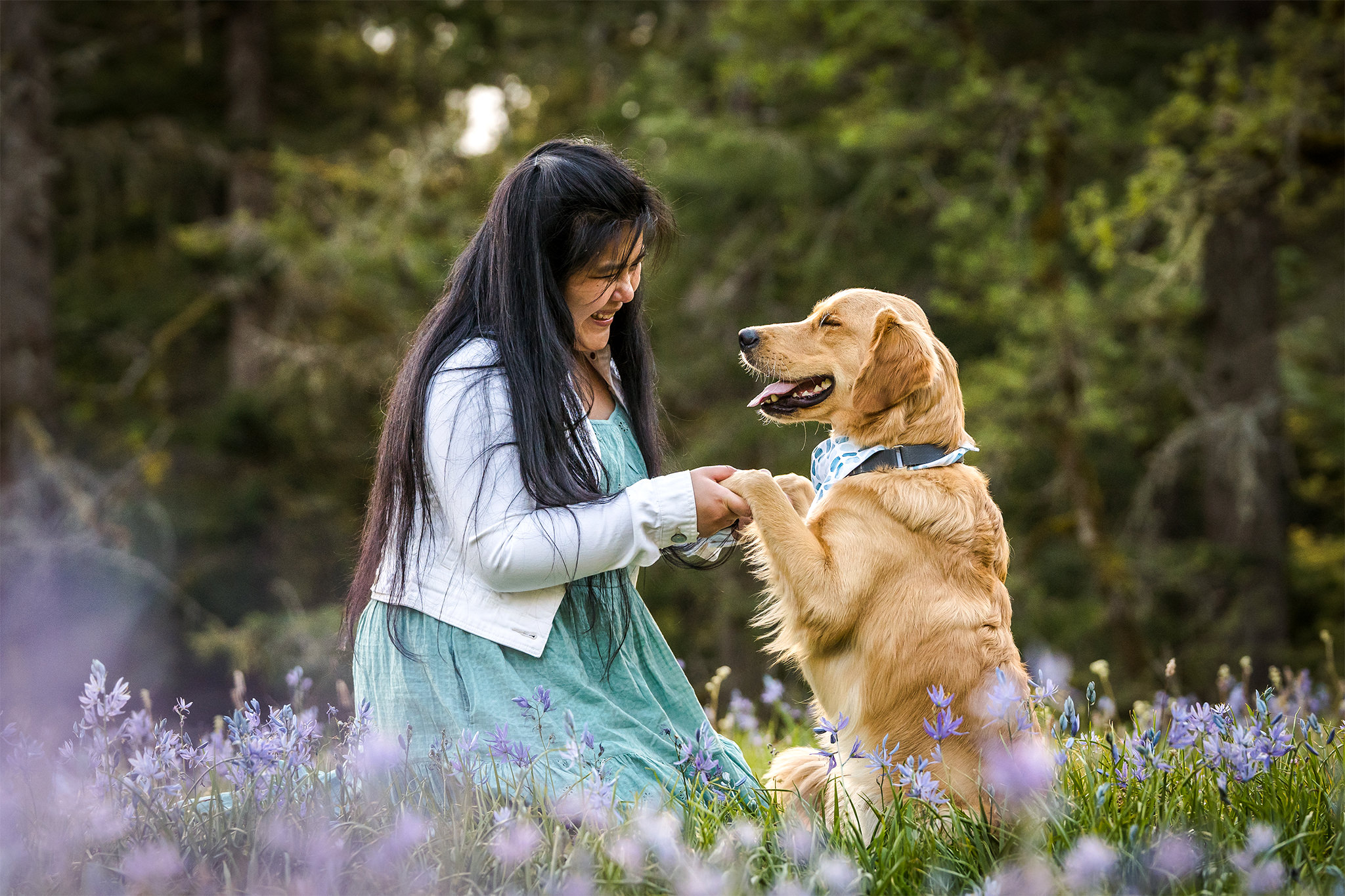 woman and dog hold hands in field of flowers