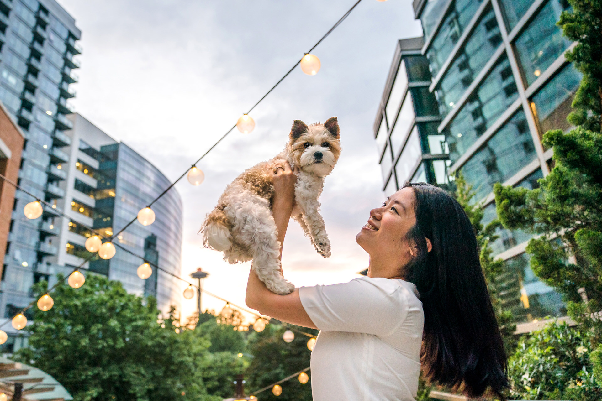 woman holds up dog with space needle in the background