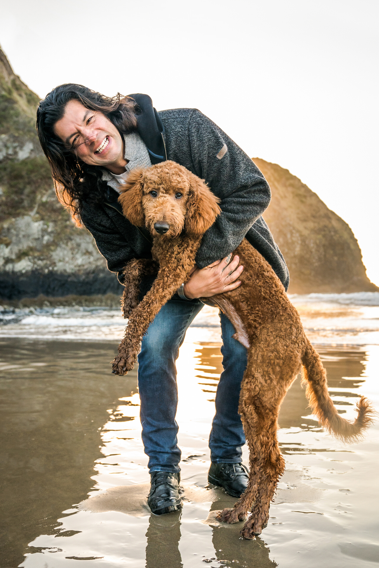 man hugs his dog on beach in Oregon