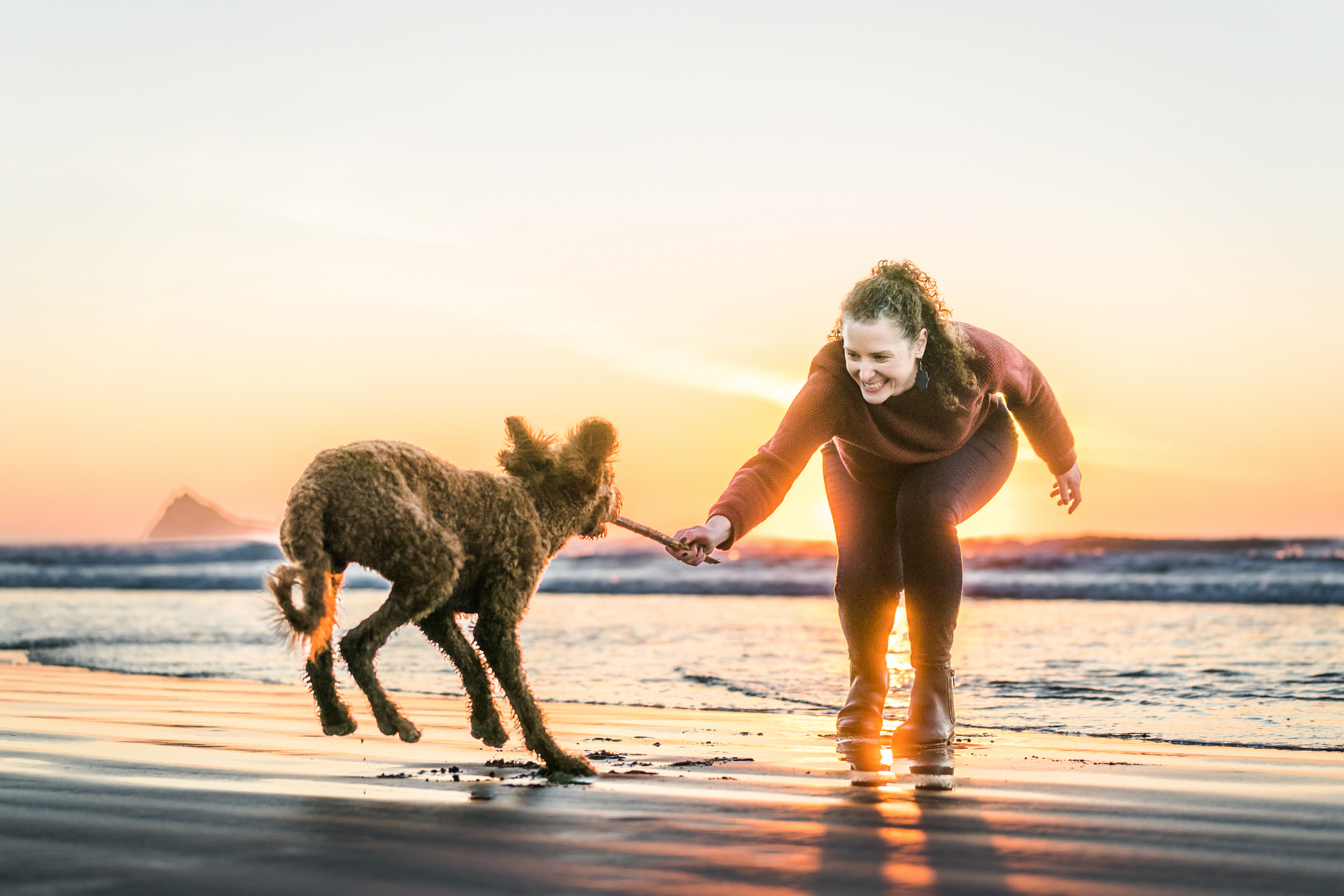 woman playing with dog at sunset