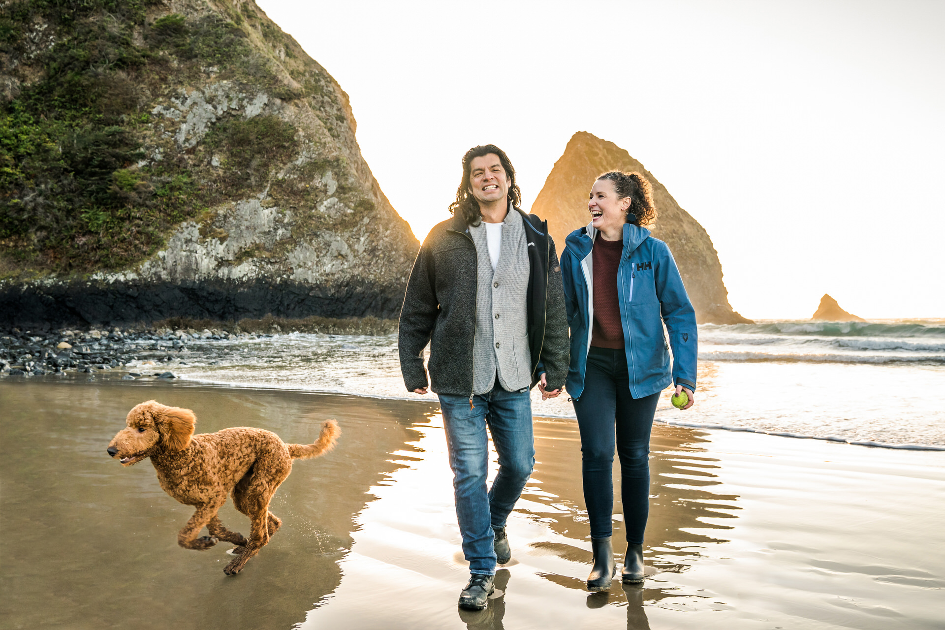 couple walks with dog on the beach in Arch Cape