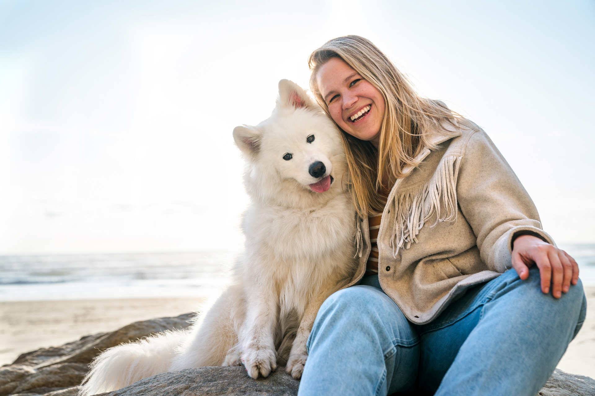 samoyed dog and woman sitting together on the beach in Oregon