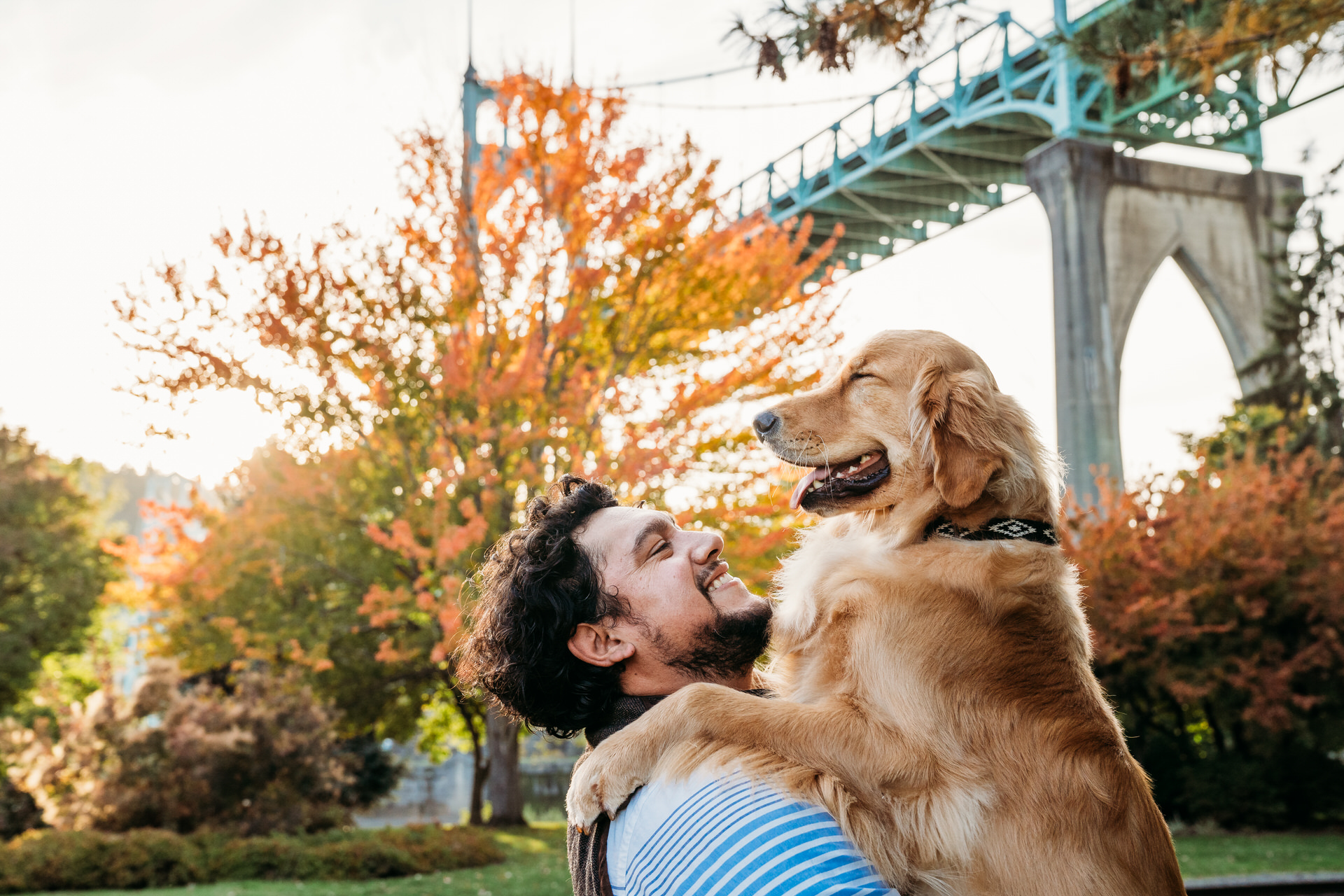 man hold dog in front of the st. johns bridge at cathedral park